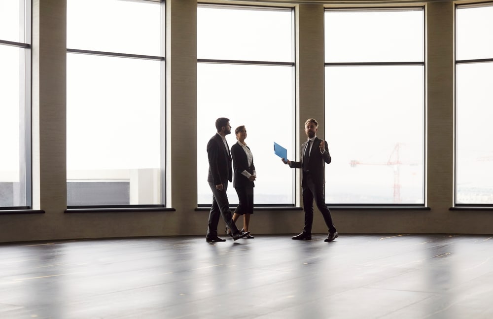 Business,Professionals,In,Suits,Walking,Through,Spacious,Modern,Office,With